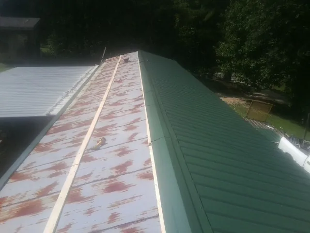 Old rusted panels beside newly installed green metal roofing — Wind Damage Roof Repair by Roofing Brothers in Katonah