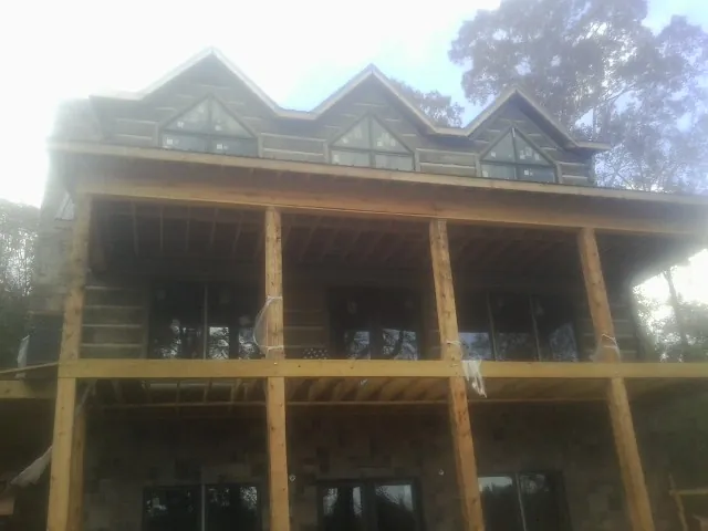 Dormers and porch framing on a large log home under construction — Roof Coating work by our crew in Katonah