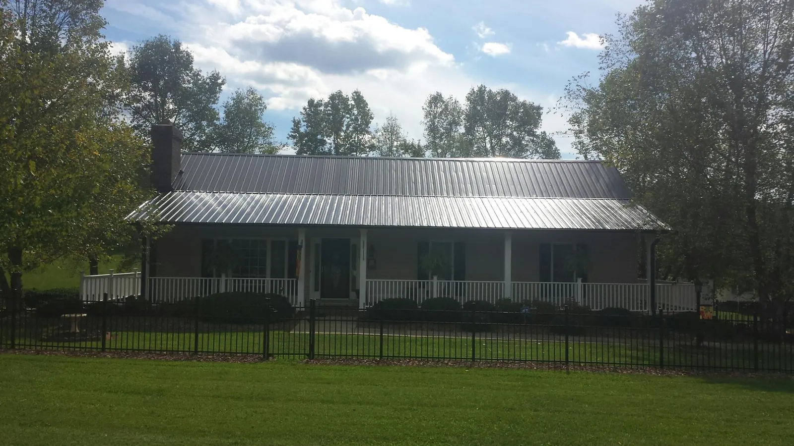 Gray metal roof on a brick ranch with a full width front porch — Gutter Guard Installation work by our crew in Katonah
