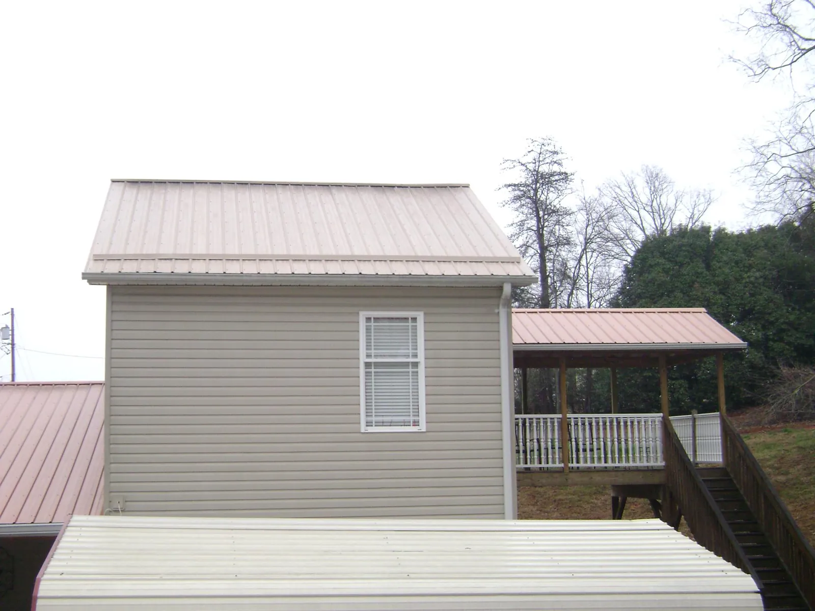 Tan metal roofs on a two story addition and attached porch, from a Roof Replacement job in Katonah