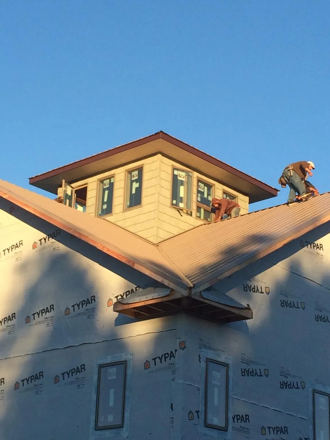 Roofers working around a rooftop cupola on a new metal roof at sunset — Roof Waterproofing in Katonah by Roofing Brothers